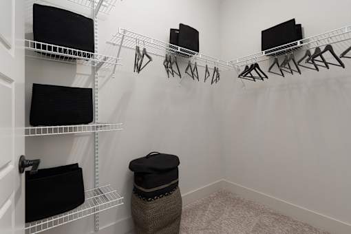 A white closet with clothes hanging and shelves.