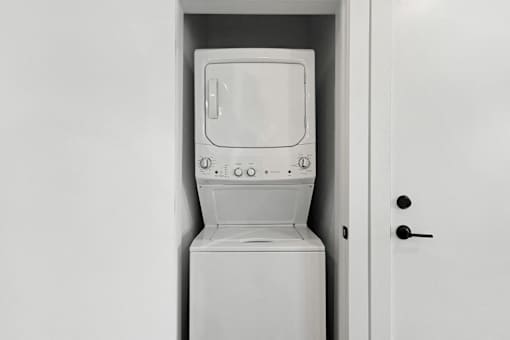 A white washing machine is sitting in a white door.