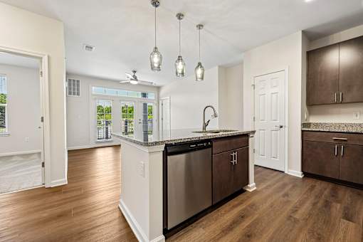 A kitchen with a stainless steel dishwasher and wooden floors.