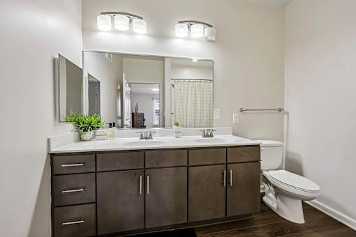 A bathroom with a white toilet and a large mirror above a sink.