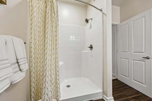 A white bathroom with a shower and a towel hanging on the wall.