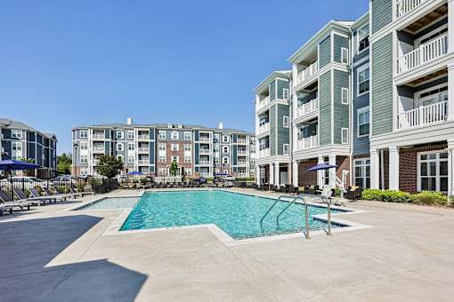 A swimming pool is surrounded by apartment buildings.