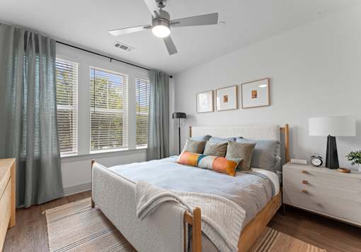A bedroom with a bed, nightstand, and window with curtains.