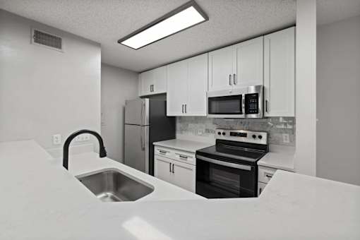 A kitchen with a sink, stove, and refrigerator.