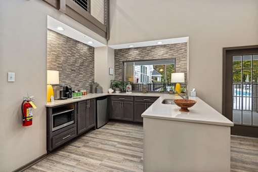 A modern kitchen with a large island and a fire extinguisher on the wall.