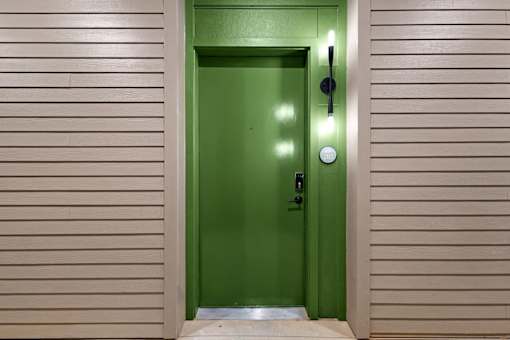 A green door with a black handle and a round doorknob.