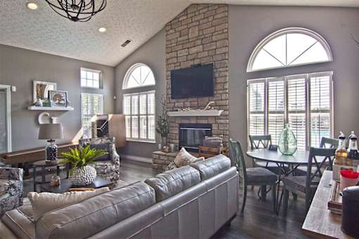 A living room with a grey couch and a stone fireplace.