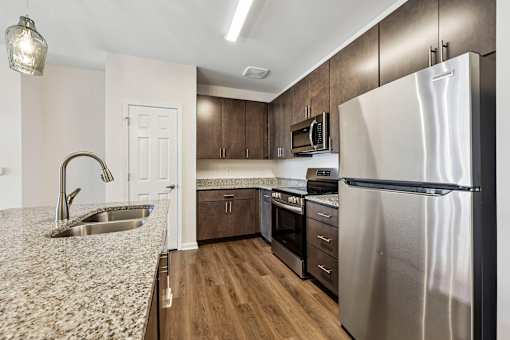 A modern kitchen with a granite countertop and stainless steel appliances.