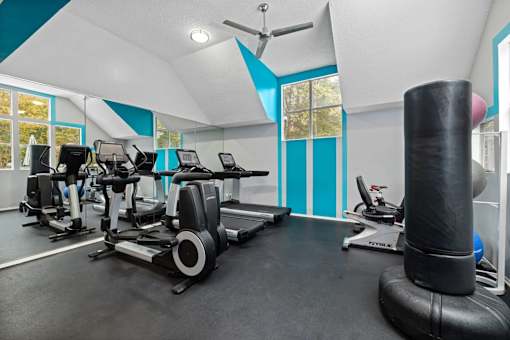 A gym with a row of treadmilers and elliptical machines.
