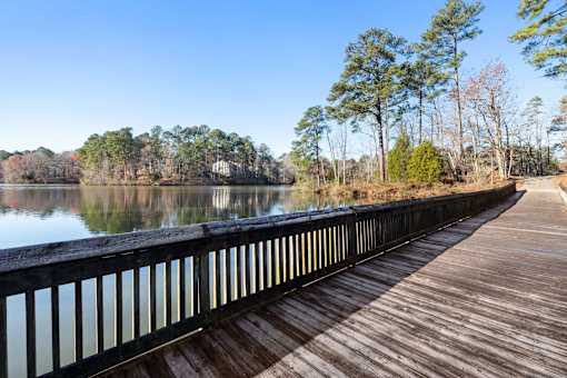 A wooden walkway runs alongside a calm body of water.