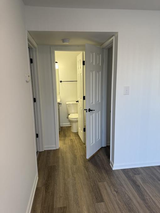 A white door is open to a bathroom with a toilet.