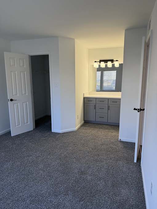 A room with a grey carpet and a white door.
