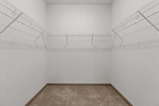 a white room with wire shelving on the wall and a carpetat Metropolis Apartments, Glen Allen, 23060