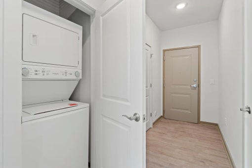 a white laundry room with a white washer and dryer and a white doorat Metropolis Apartments, Virginia