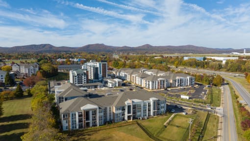 an aerial view of an apartment complex with a river and mountains in the background