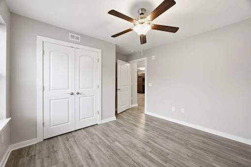 A room with a ceiling fan and a white door.