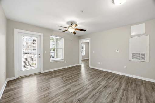 A spacious room with a ceiling fan and wooden flooring.