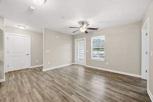 A room with a ceiling fan and wooden flooring.