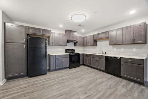 A kitchen with dark wood cabinets and a black refrigerator.