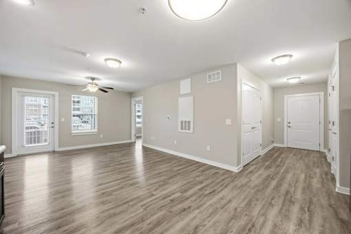 A spacious room with wood flooring and white walls.