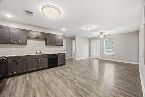A kitchen with wooden floors and dark brown cabinets.