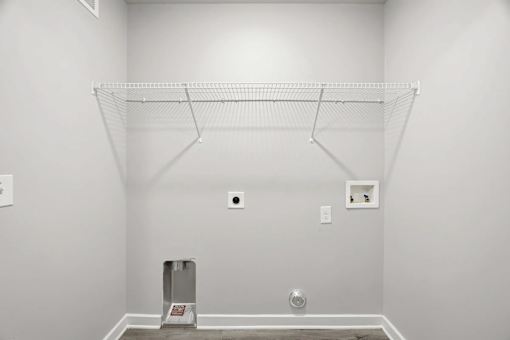 A white wall with a shelf and a small picture on it.