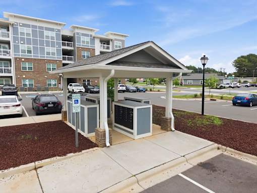 A parking lot with a covered parking area and a building in the background.