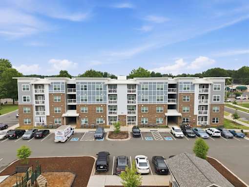 A large apartment complex with a parking lot in front.