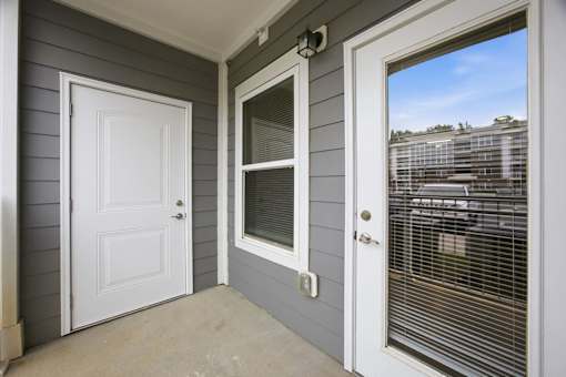 A white door is on the left and a window with blinds is on the right.