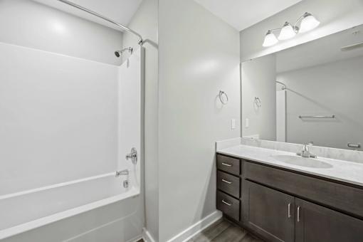 A bathroom with a white tub, sink, and mirror.