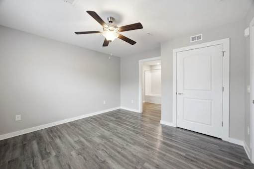 A room with a ceiling fan and wood flooring.