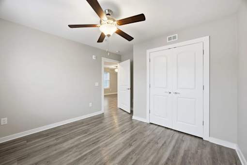 A room with a ceiling fan and a white door.