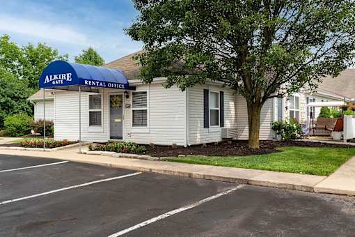 A white building with a blue awning that says Alkire Gate Rental Office.