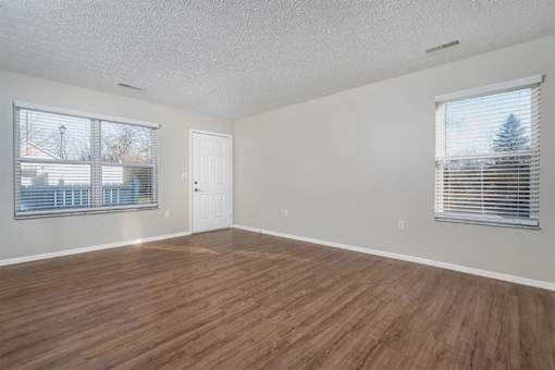 Empty room with wooden flooring and white walls.