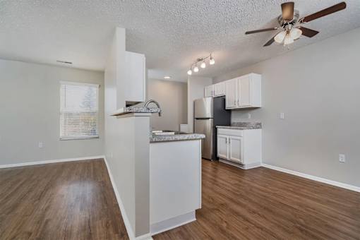 A kitchen with white cabinets and a wooden floor.