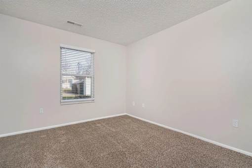 A room with a window and carpeted floor.