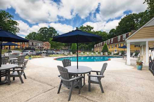 A pool area with a table and chairs and umbrellas.