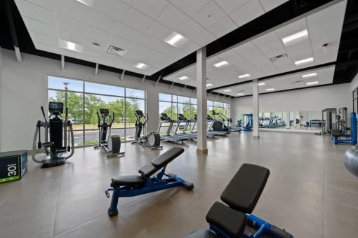 a gym with cardio equipment and weights in a building with large windowsat Metropolis Apartments, Glen Allen, 23060