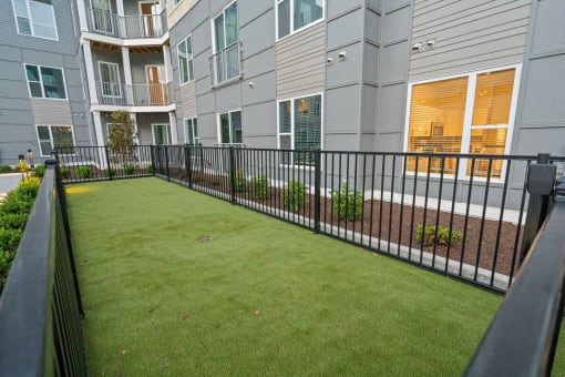 an apartment yard with a fence in front of a buildingat Metropolis Apartments, Glen Allen, VA 23060