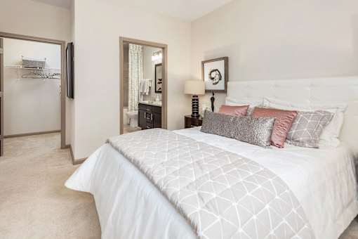A bedroom with a large bed and a mirror on the wall.