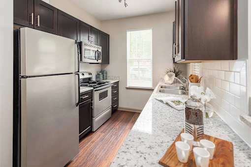 A kitchen with a refrigerator, oven, and microwave.