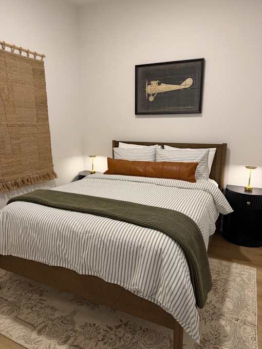 A bed with a striped comforter and a brown pillow is in the image.