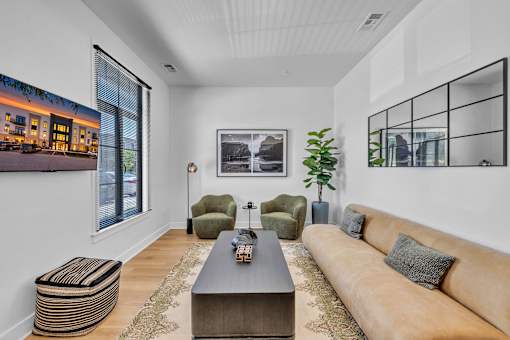 A living room with a brown couch, a coffee table, and a large window.