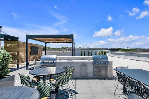 A patio with a table and chairs and a grill.