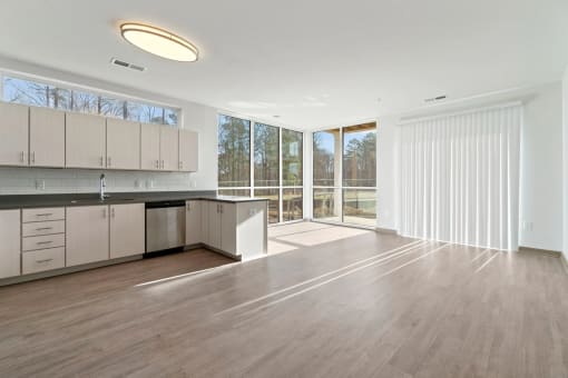 an empty living room with a kitchen and sliding glass doorsat Metropolis Apartments, Glen Allen Virginia