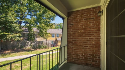 a porch with a brick wall and a black railing
