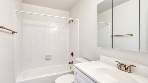 a white bathroom with a tub sink and mirror
