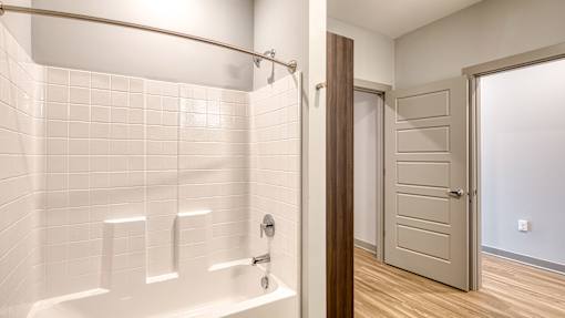A white tiled bathroom with a wooden door.