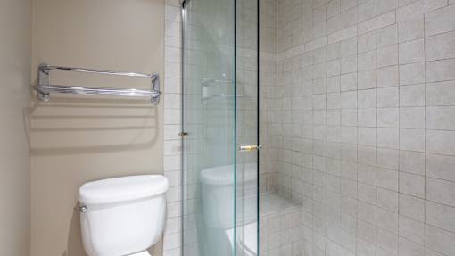 A white toilet sits next to a glass shower door in a tiled bathroom.