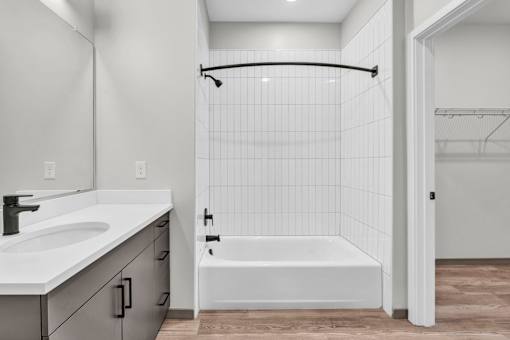 A white bathroom with a white tub and a white sink.